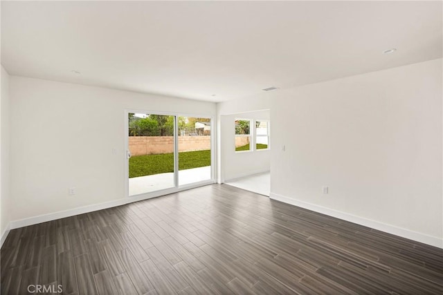 unfurnished room with baseboards, dark wood-type flooring, and visible vents
