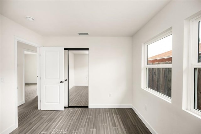 unfurnished bedroom featuring baseboards, wood finished floors, visible vents, and a closet