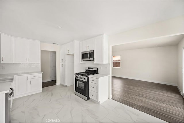 kitchen with decorative backsplash, appliances with stainless steel finishes, white cabinets, and light countertops