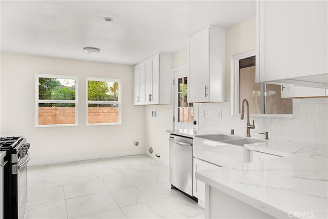 kitchen featuring plenty of natural light, appliances with stainless steel finishes, light stone counters, and a sink