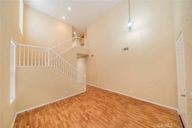 3882 Strand Way, Perris, CA 92571 - unfurnished living room featuring a towering ceiling, wood finished floors, baseboards, stairs, and recessed lighting