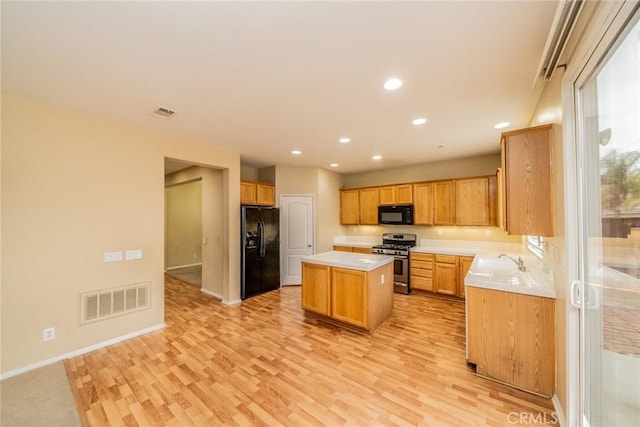 3882 Strand Way, Perris, CA 92571 - kitchen with black appliances, a kitchen island, light wood-style floors, light countertops, and recessed lighting