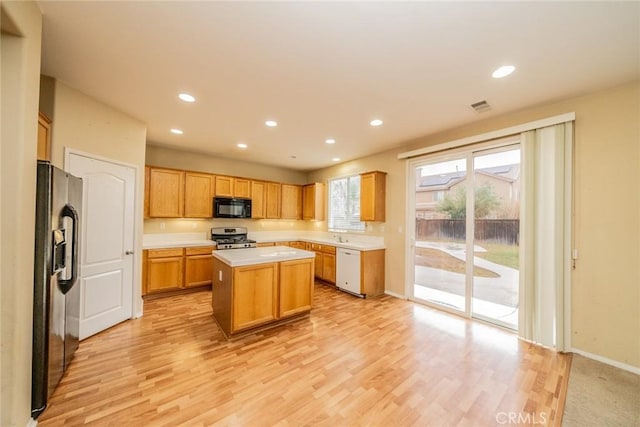 3882 Strand Way, Perris, CA 92571 - kitchen featuring black appliances, recessed lighting, light wood-style floors, a center island, and light countertops