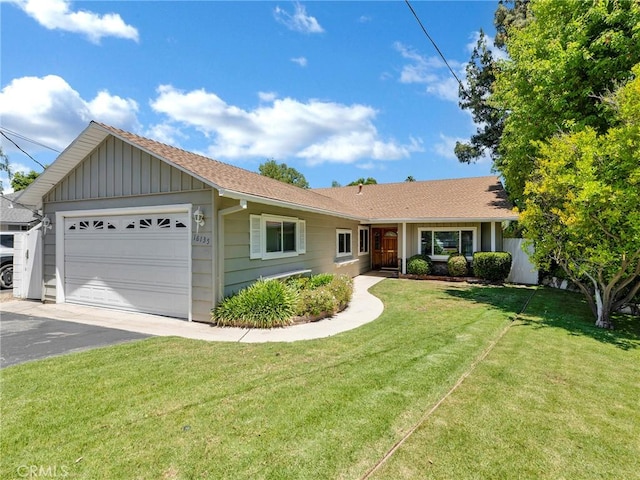 ranch-style home featuring an attached garage, asphalt driveway, a front yard, and board and batten siding
