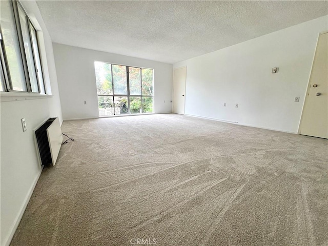 61 Calle Cadiz Unit Q, Laguna Woods, CA 92530 - unfurnished living room featuring radiator heating unit, carpet floors, a textured ceiling, and baseboards