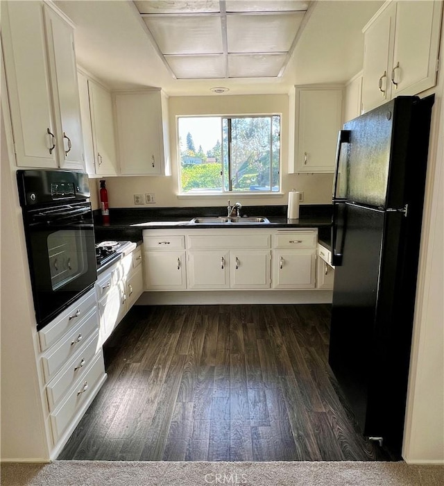 61 Calle Cadiz Unit Q, Laguna Woods, CA 92530 - kitchen with black appliances, a sink, dark countertops, dark wood-type flooring, and white cabinets