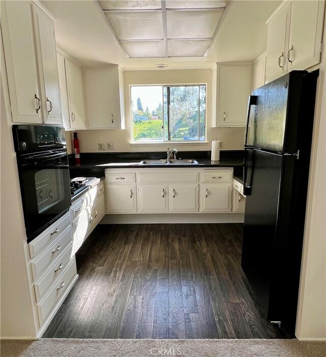 61 Calle Cadiz Unit Q, Laguna Woods, CA 92530 - kitchen featuring black appliances, dark countertops, dark wood finished floors, and white cabinets