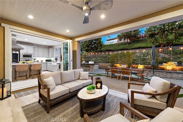 view of patio / terrace with a ceiling fan, an outdoor kitchen, outdoor dining space, fence, and an outdoor hangout area