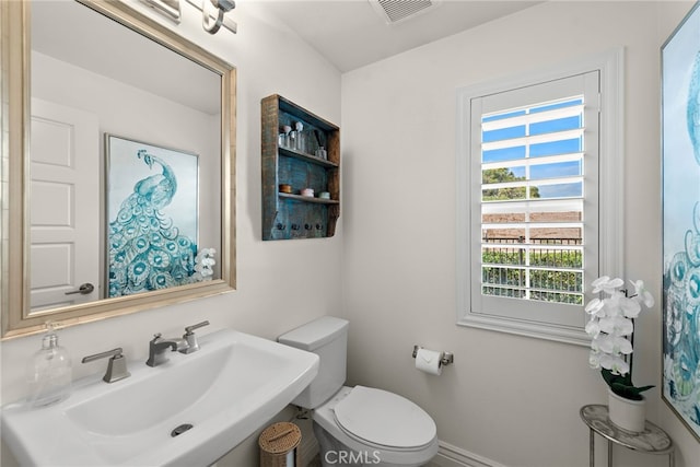 bathroom featuring a sink, toilet, and visible vents
