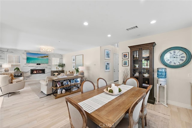 dining room featuring a premium fireplace, recessed lighting, baseboards, visible vents, and light wood-type flooring
