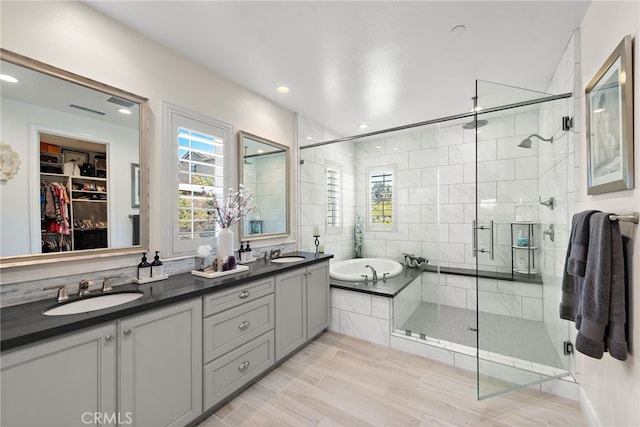 full bathroom with a sink, double vanity, a stall shower, and a bath