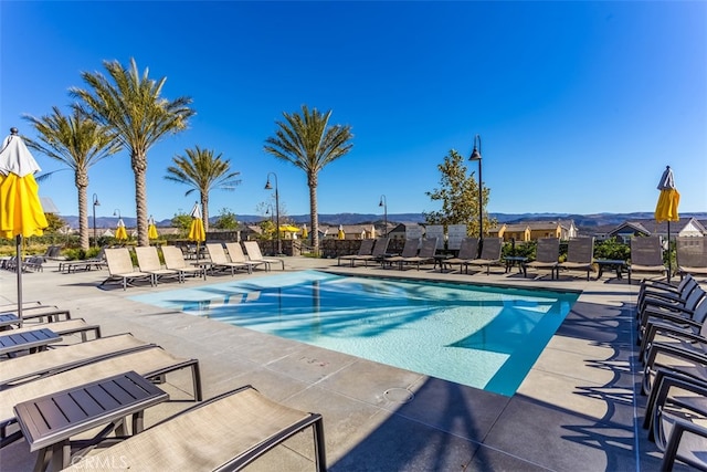community pool featuring a patio area, a mountain view, and fence
