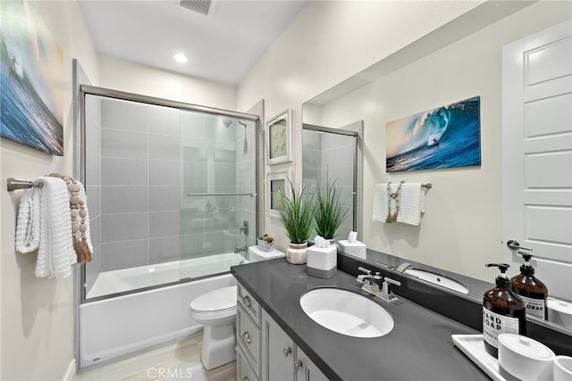 bathroom with toilet, enclosed tub / shower combo, wood finished floors, vanity, and recessed lighting