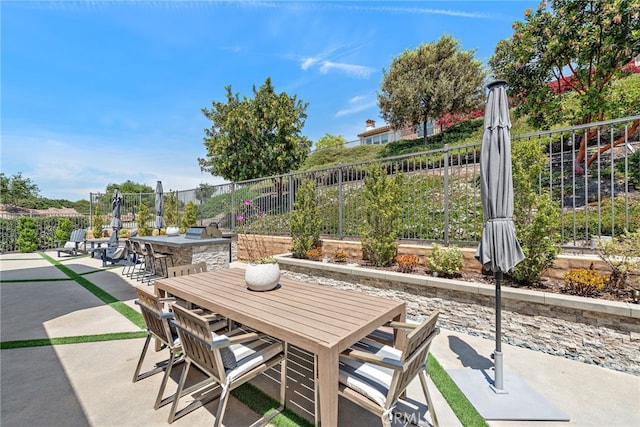 view of patio with an outdoor kitchen, outdoor dining area, a fenced backyard, and outdoor dry bar