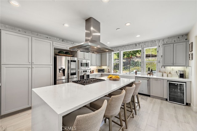 kitchen with stainless steel appliances, gray cabinetry, beverage cooler, and island exhaust hood