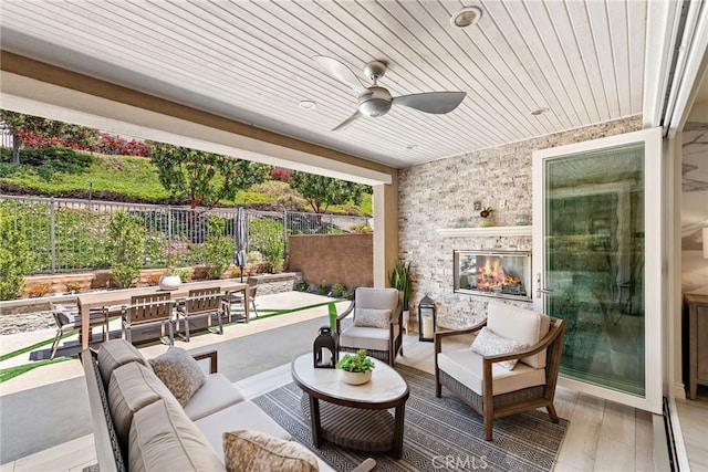 view of patio / terrace featuring a ceiling fan, an outdoor living space with a fireplace, and a fenced backyard