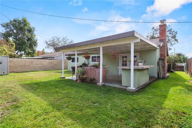 exterior space with a patio, a fenced backyard, a yard, and a chimney
