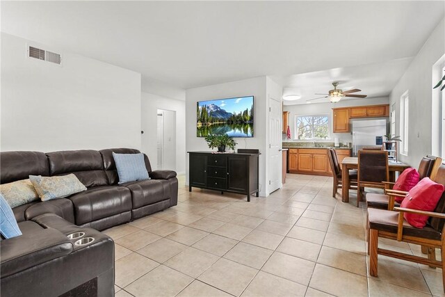 living area featuring light tile patterned floors, a ceiling fan, and visible vents