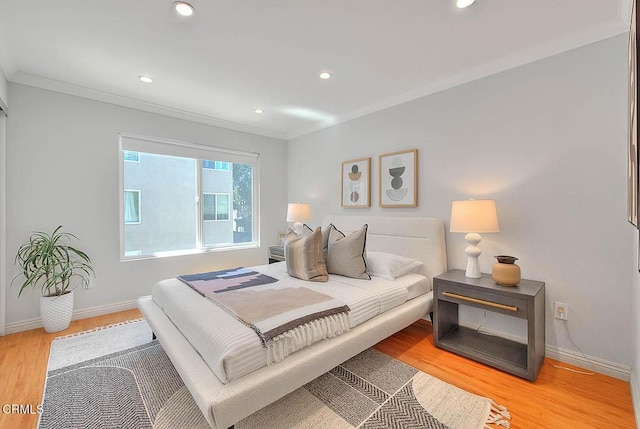bedroom with light wood finished floors, baseboards, and ornamental molding