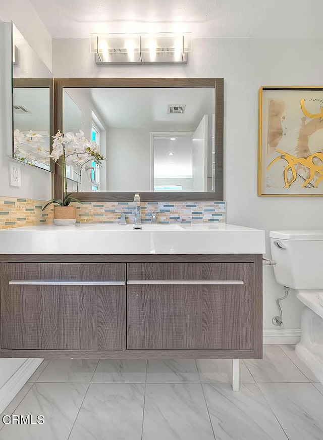 bathroom with marble finish floor, visible vents, toilet, vanity, and decorative backsplash