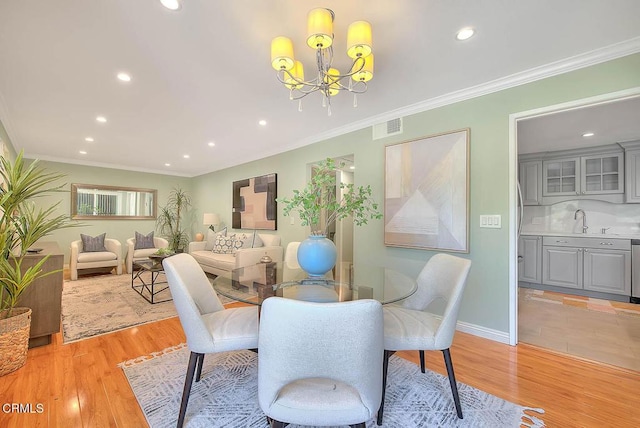 dining space with ornamental molding, a chandelier, recessed lighting, and light wood finished floors