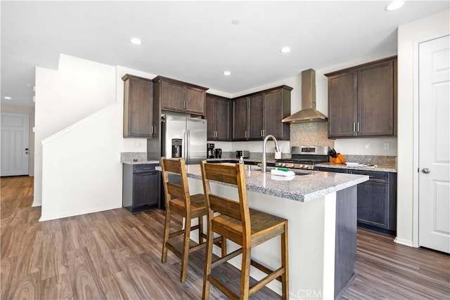 3308 Jack Rabbit Ct, Perris, CA 92570 - kitchen featuring stainless steel appliances, dark wood-style floors, dark brown cabinets, wall chimney range hood, and light stone countertops