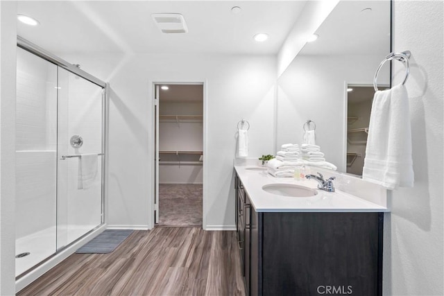 3308 Jack Rabbit Ct, Perris, CA 92570 - bathroom featuring wood finished floors, a sink, a stall shower, a spacious closet, and double vanity