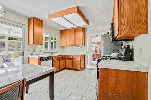1426 Crestview Dr, Oceanside, CA 92056 - kitchen featuring white dishwasher, brown cabinets, gas range oven, light tile patterned floors, and freestanding refrigerator