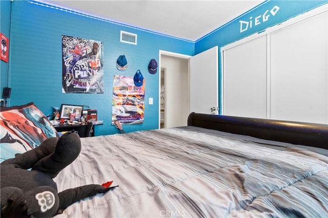 bedroom featuring a textured wall, visible vents, and a closet