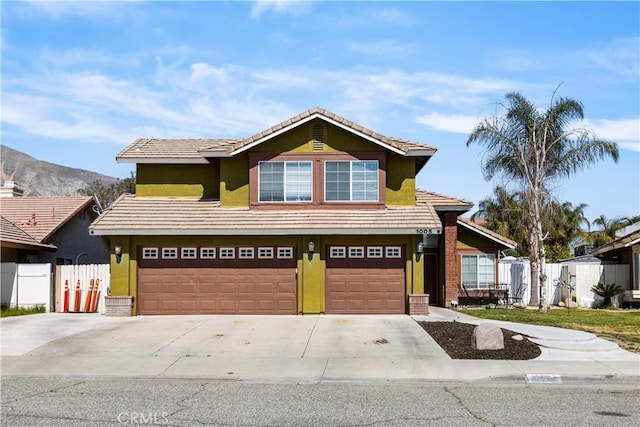 traditional-style house with fence, concrete driveway, stucco siding, and a garage