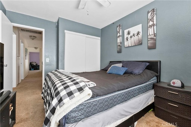carpeted bedroom featuring a closet, ceiling fan, and visible vents