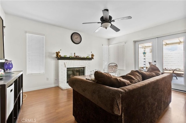 living room with ceiling fan, baseboards, wood finished floors, and a fireplace