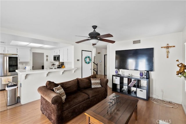 living area featuring a ceiling fan, light wood-style floors, and visible vents