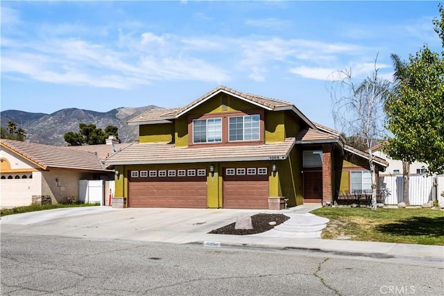 view of front of house with a tile roof, a mountain view, fence, an attached garage, and stucco siding