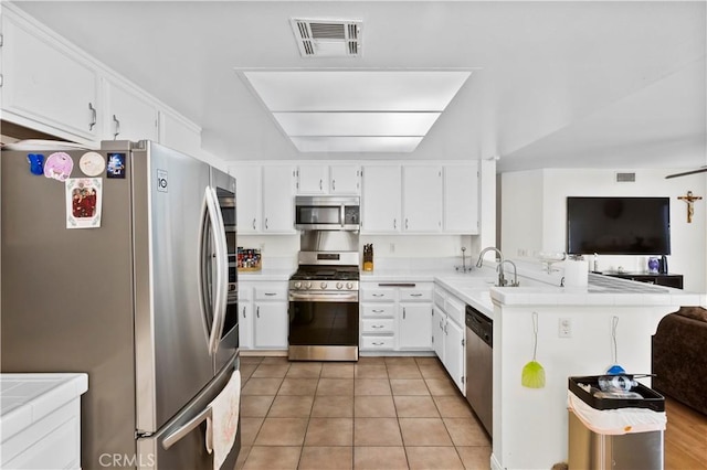 kitchen featuring white cabinets, stainless steel appliances, a peninsula, open floor plan, and visible vents