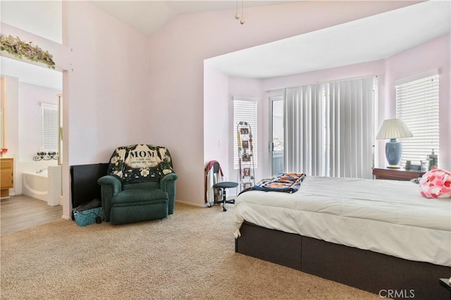carpeted bedroom with vaulted ceiling, multiple windows, and ensuite bathroom