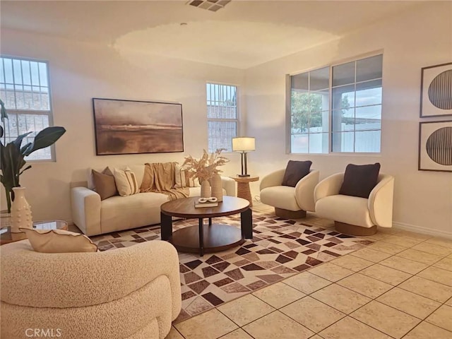 living room featuring light tile patterned floors, baseboards, plenty of natural light, and visible vents