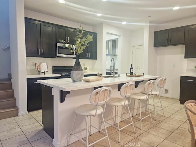 kitchen with a sink, light countertops, stainless steel microwave, and recessed lighting