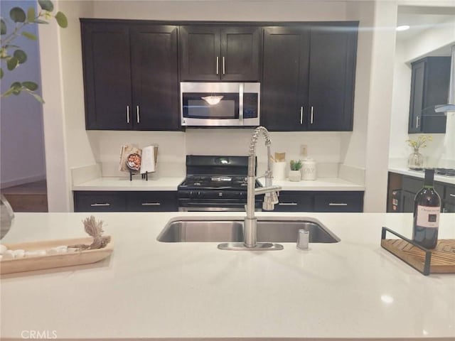 kitchen with a sink, light countertops, stainless steel microwave, and black gas stove