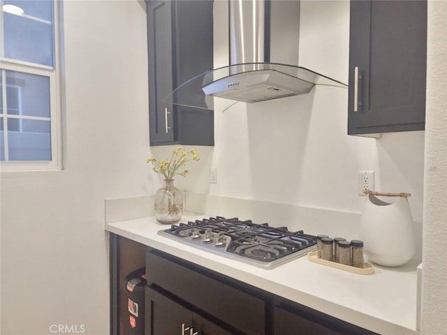 kitchen with stainless steel gas cooktop, wall chimney exhaust hood, and light countertops