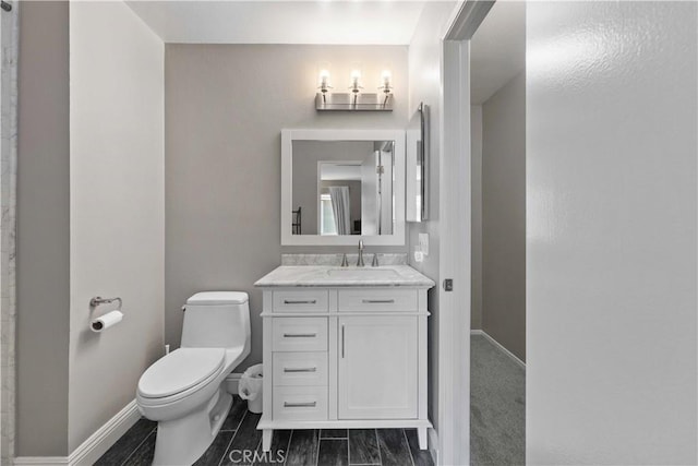 bathroom featuring toilet, vanity, and baseboards