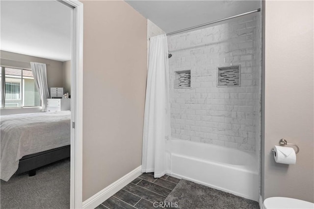 ensuite bathroom featuring ensuite bathroom, baseboards, shower / bathtub combination with curtain, and toilet