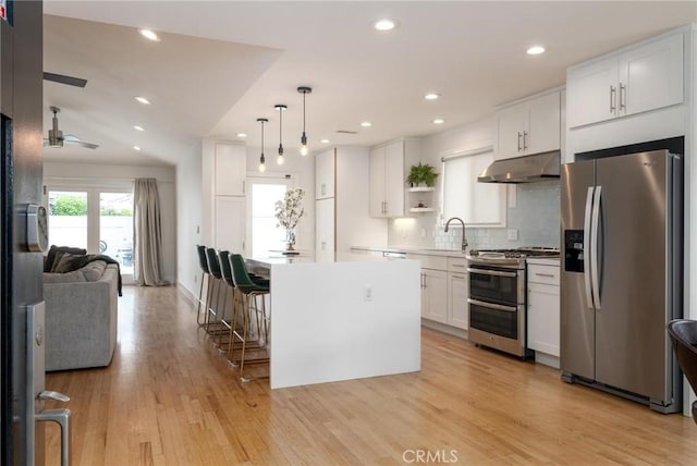 kitchen featuring white cabinetry, decorative backsplash, open shelves, under cabinet range hood, and appliances with stainless steel finishes