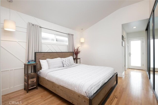 bedroom featuring vaulted ceiling, light wood finished floors, and baseboards
