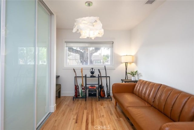 sitting room featuring light wood finished floors, baseboards, visible vents, and a notable chandelier