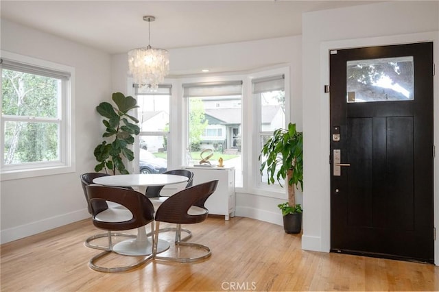 foyer entrance featuring baseboards, a notable chandelier, and light wood-type flooring