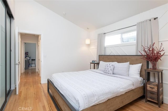 bedroom featuring light wood-style flooring and vaulted ceiling