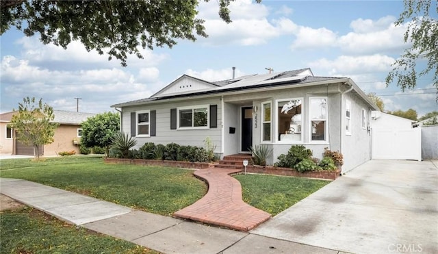 bungalow featuring a front lawn, a gate, and solar panels