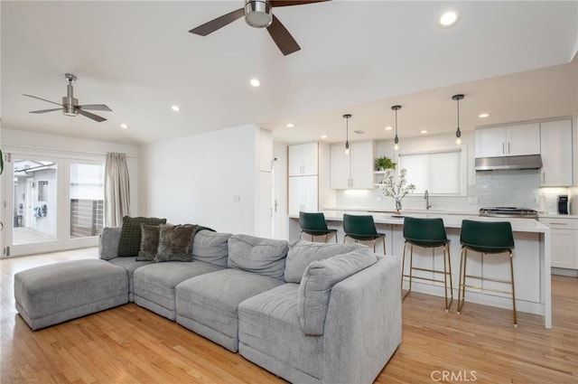 living area with a ceiling fan, light wood-type flooring, and recessed lighting