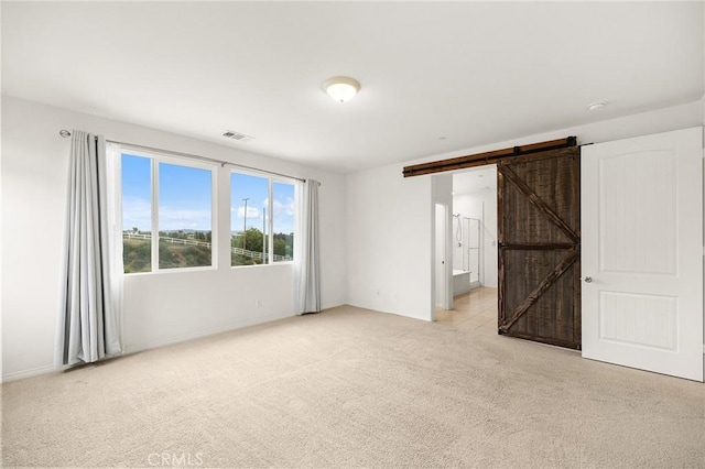 37544 River Oats Ln, Murrieta, CA 92563 - unfurnished bedroom with a barn door, visible vents, light carpet, connected bathroom, and baseboards